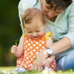 parent with baby in first year outside in grass