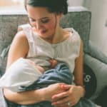 mom breastfeeding baby in chair at home