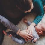 newborn baby being greeted by older siblings