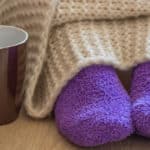 woman in cozy purple socks under blanket
