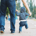dad walks young baby in park