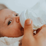 newborn baby drinking milk from bottle
