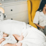 baby in cradle with mom working in chair by her side