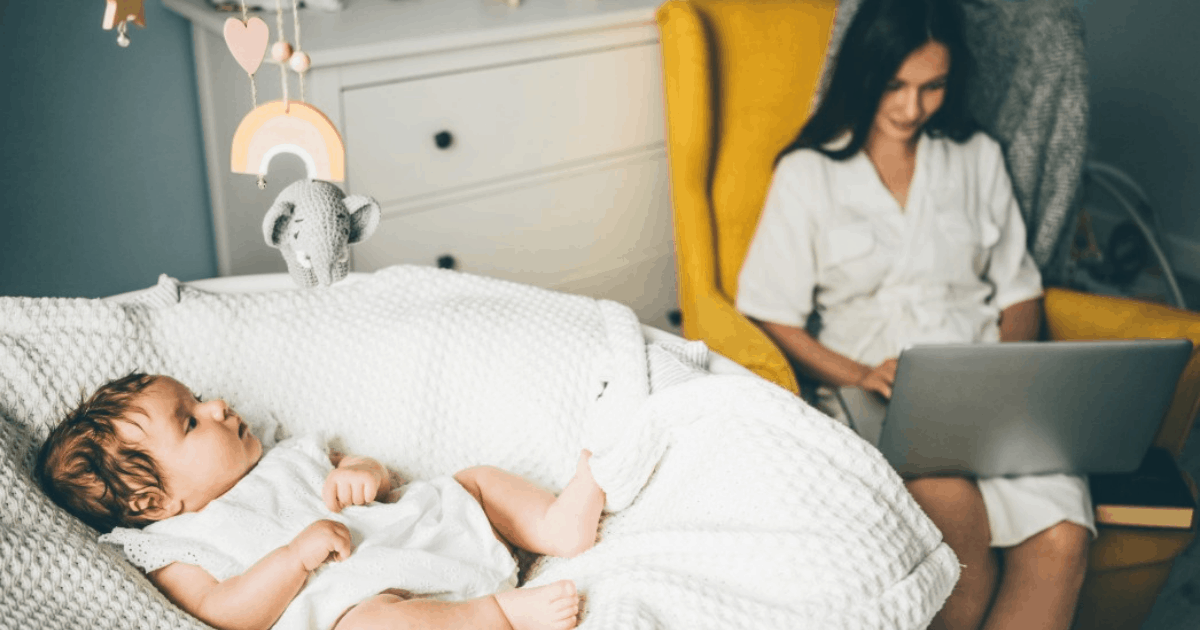 baby in cradle with mom working in chair by her side