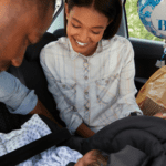 new parents in the car putting newborn baby in car seat coming home from the hospital