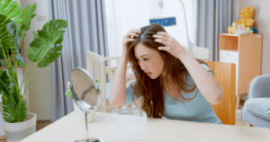New mother looking at her postpartum hair loss in the mirror
