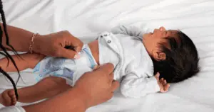 A mom changing newborn poop diaper