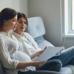 Pregnant couple sitting with a laptop making a postpartum plan