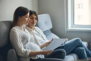 Pregnant couple sitting with a laptop and a postpartum plan