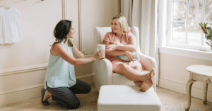 A doula offering a cup of tea to a new mom, why choose a doula agency?
