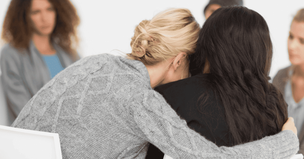 Woman embracing another women in a therapy group