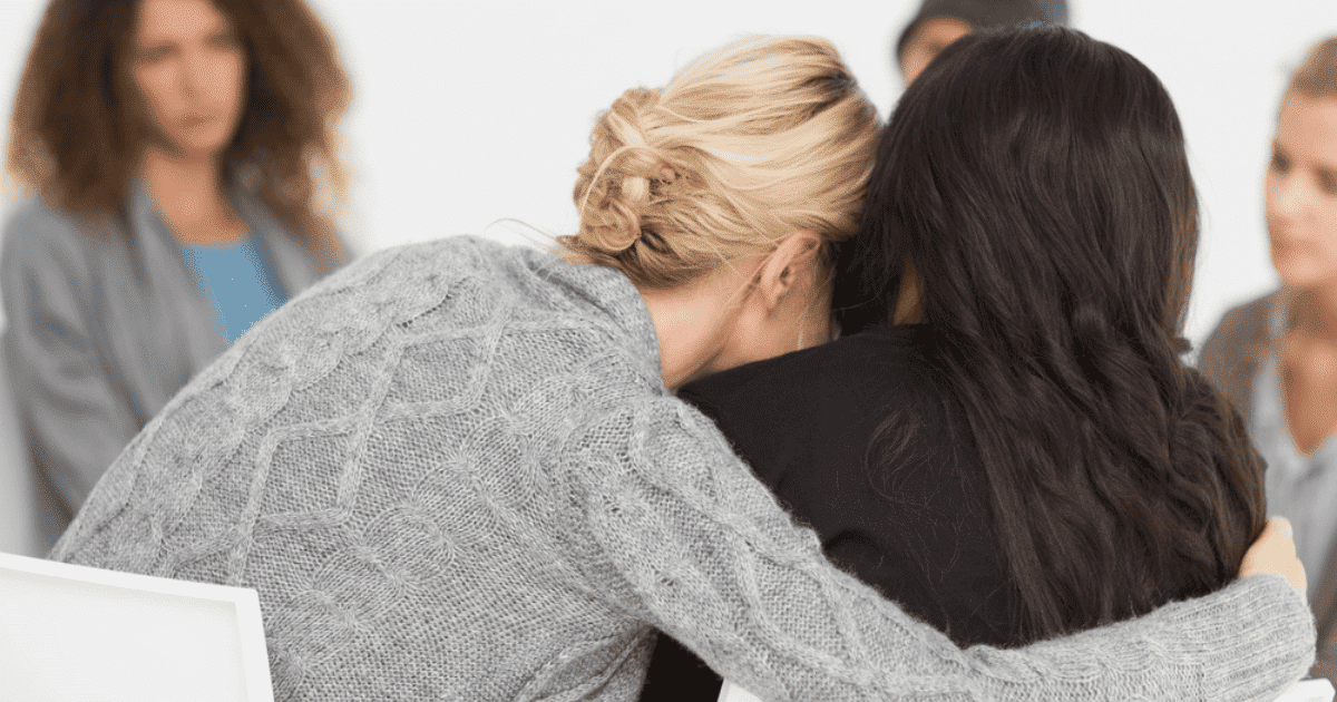 Woman embracing another women in a therapy group