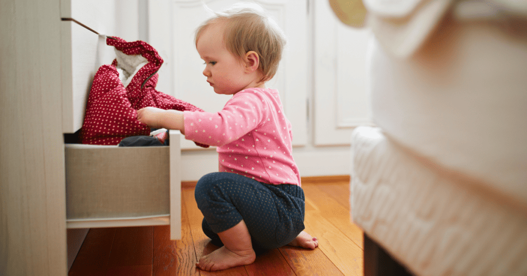 baby playing in a drawer in the bedroom