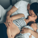 Mom and Dad kissing, baby lying next to them