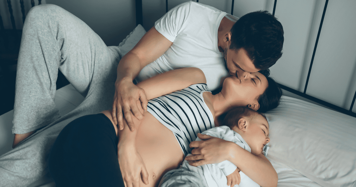 Mom and Dad kissing, baby lying next to them