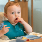 Baby eating solid foods in his highchair