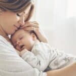 New mom holding baby on chest at home