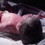 newborn baby at hospital with cord attached and vernix