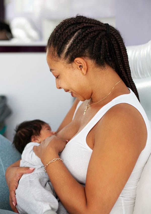 new mom breastfeeding baby held against chest