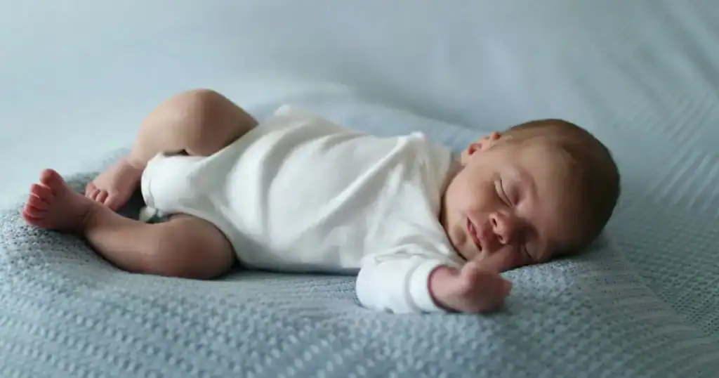newborn baby sleeping on mattress in onesie