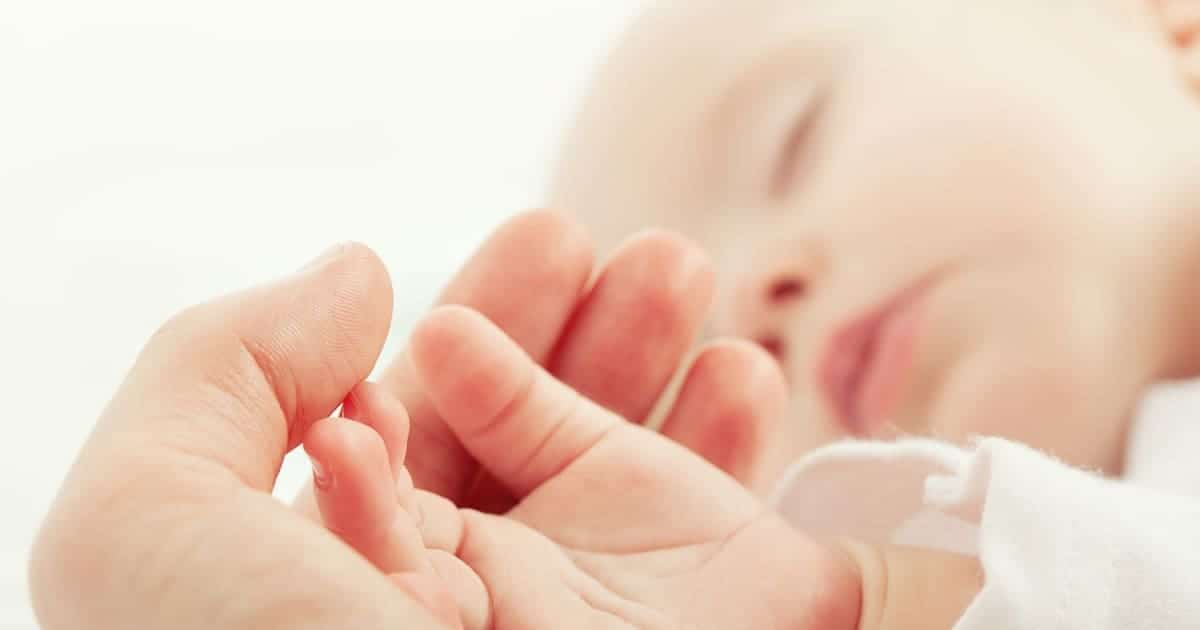 newborn sleeping holding parents hand