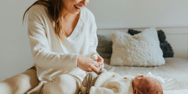 postpartum mom dressing baby on bed