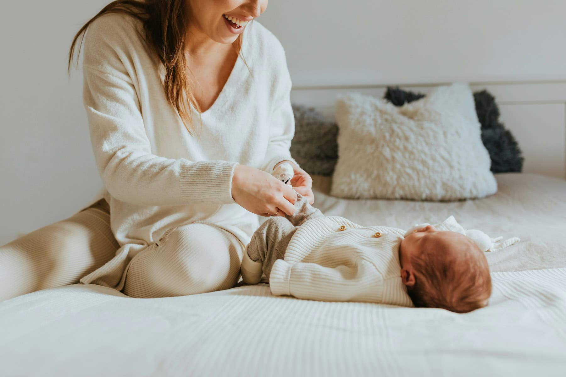 postpartum mom dressing baby on bed