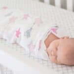 sleeping baby swaddled in crib