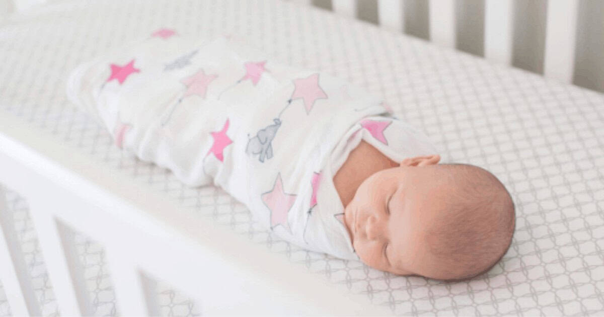 sleeping baby swaddled in crib