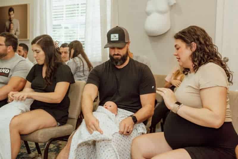 Pregnant couple practice swaddling at Tampa FL newborn care class with Buddha Belly Doulas