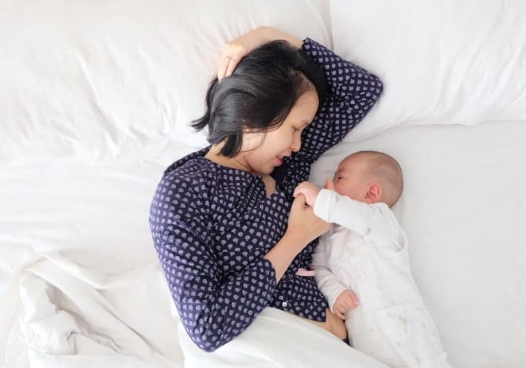 new mom breastfeeding in bed