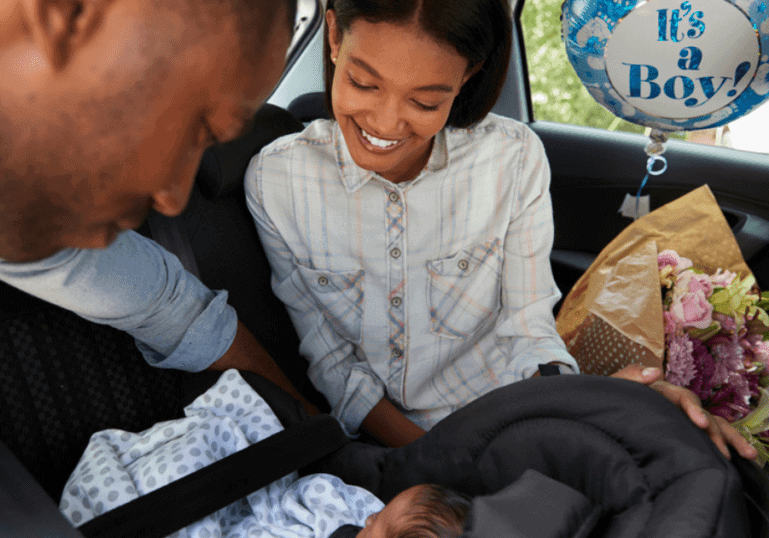 new parents in the car putting newborn baby in car seat coming home from the hospital