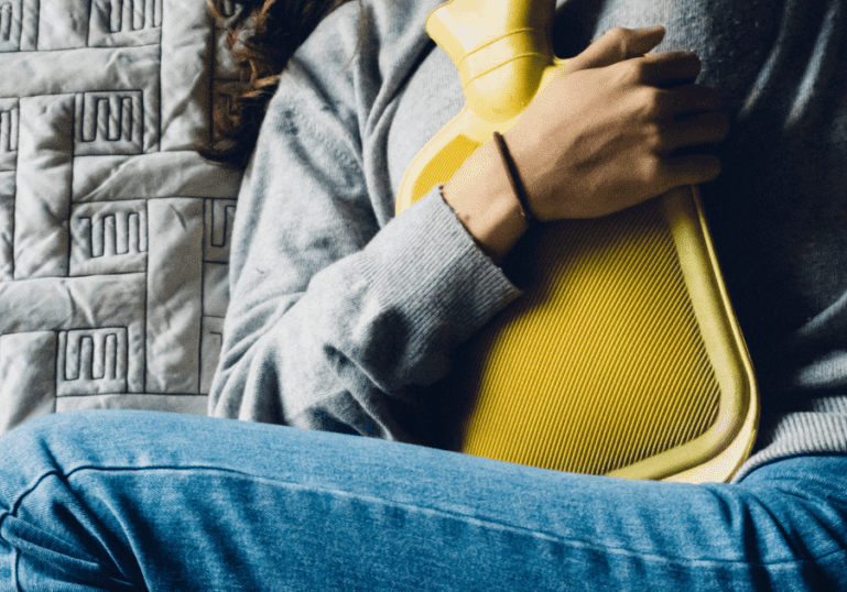 Holding a Hot Water Bottle on her abdomen