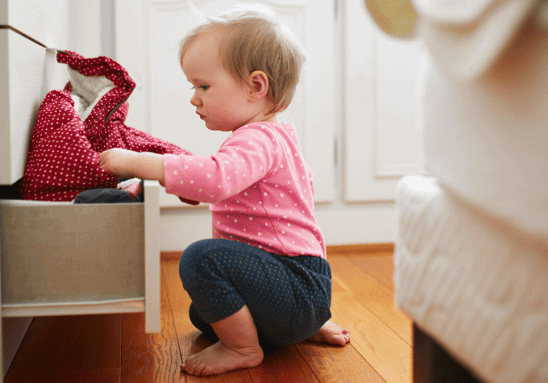 baby playing in a drawer in the bedroom