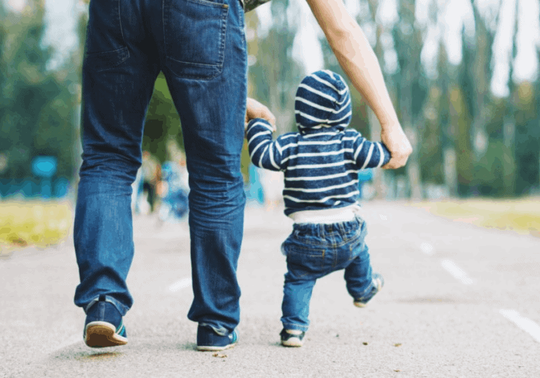 dad walks young baby in park