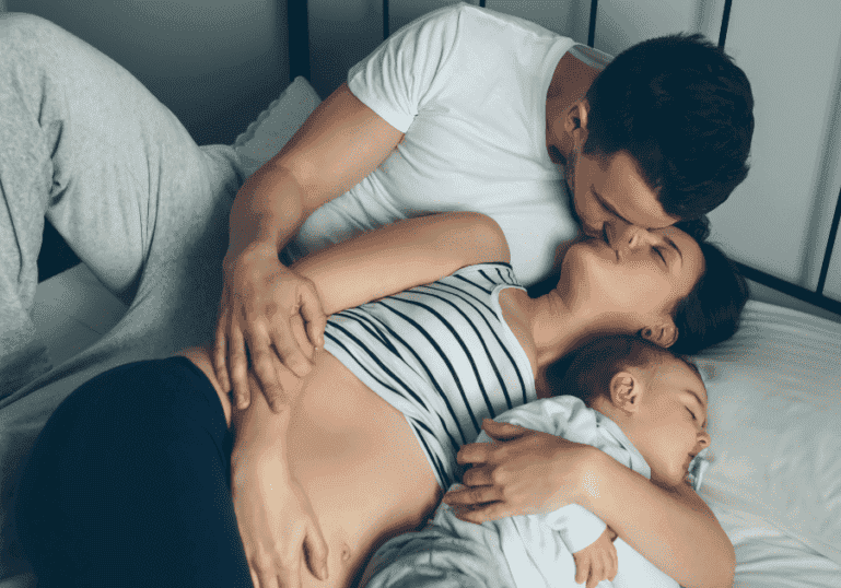Mom and Dad kissing, baby lying next to them