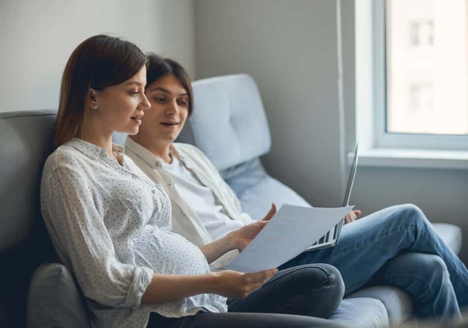 Pregnant couple sitting with a laptop making a postpartum plan