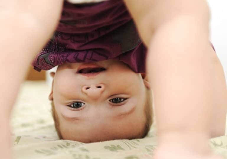 baby playing with bum in air