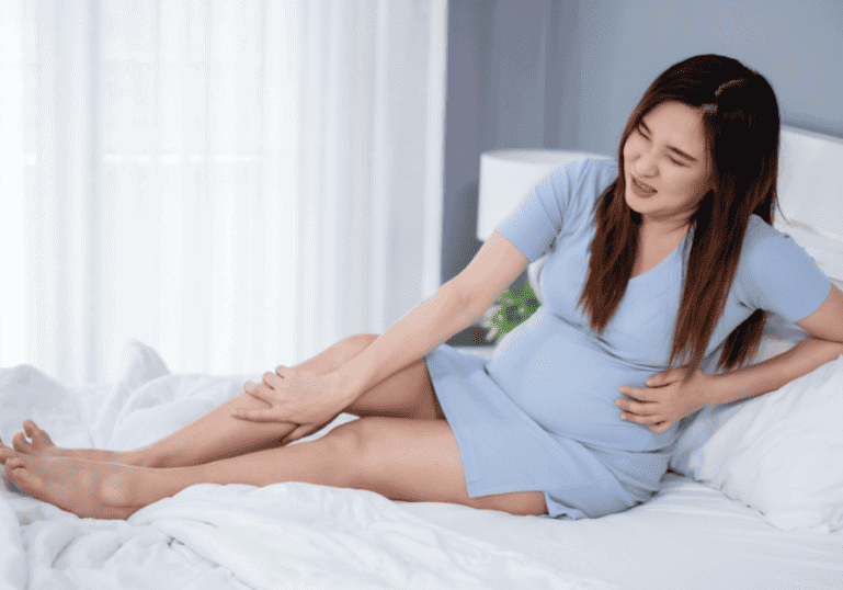Pregnant women holding leg in pain