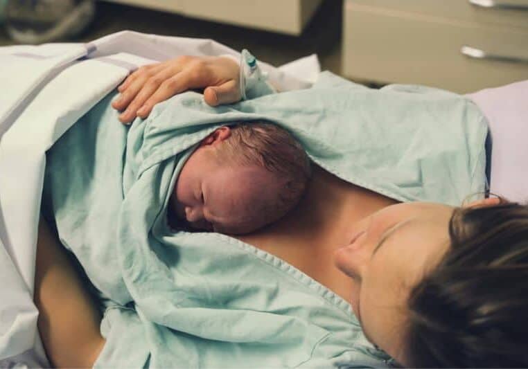 New mom with baby on chest in hospital birth