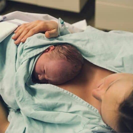 New mom with baby on chest in hospital birth