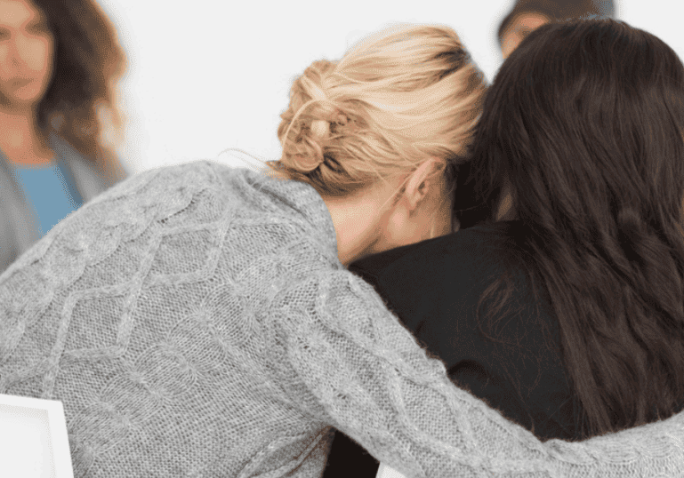 Woman embracing another women in a therapy group