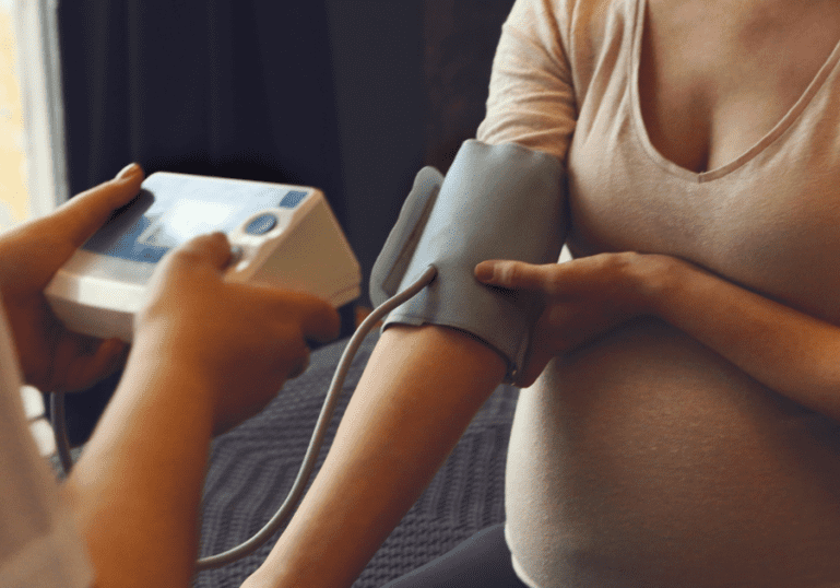 taking blood pressure of a pregnant mother monitoring for preeclampsia