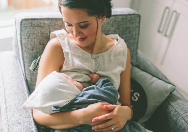 mom breastfeeding baby in chair at home