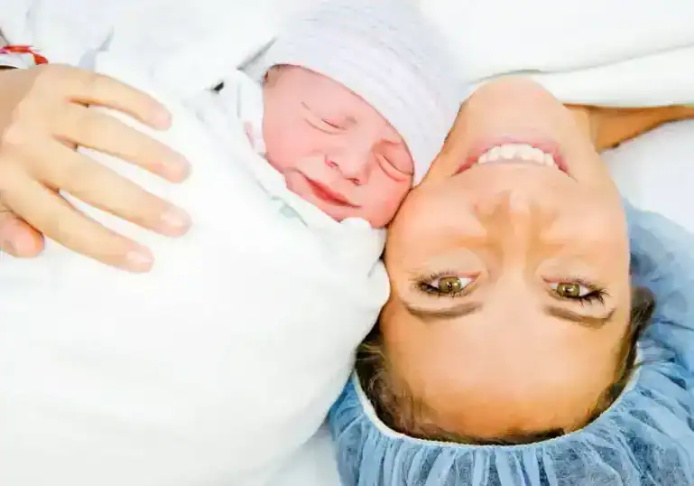mom in or after c-section with her baby swaddled