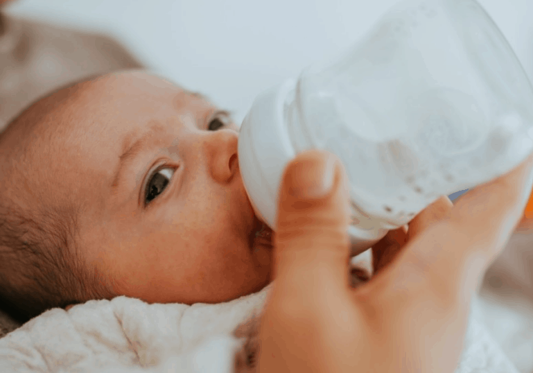 newborn baby drinking milk from bottle