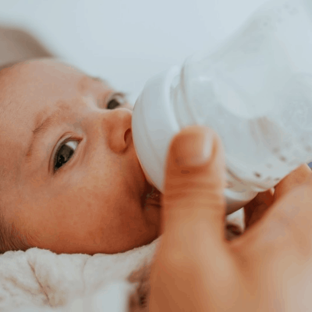 newborn baby drinking milk from bottle
