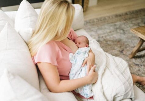 New mom in Tampa FL breastfeeding on couch at home