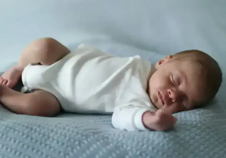 newborn baby sleeping on mattress in onesie
