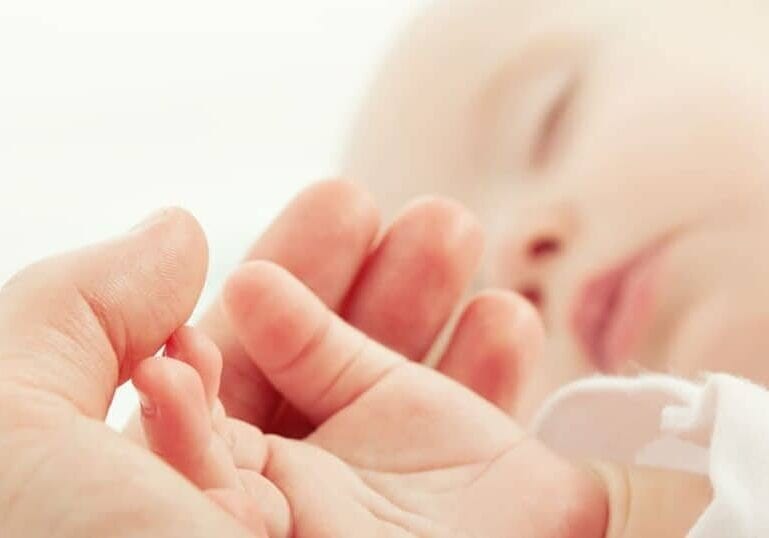newborn sleeping holding parents hand